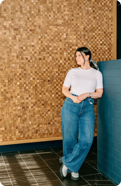 Rebecca leaning against a textured wood wall.