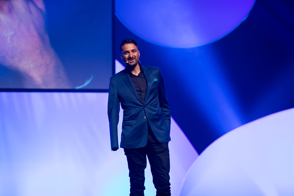 Sam Cawthorn speaking on a blue-lit stage
