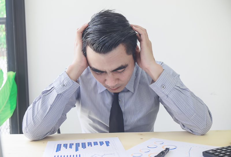 Business owner stressed over low conversion rates and lost leads while reviewing marketing analytics data.