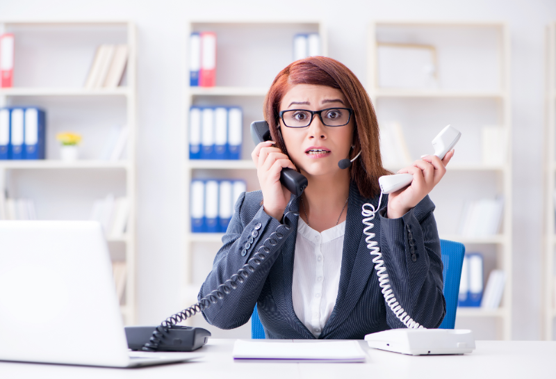 Stressed customer service representative answering multiple calls, illustrating missed calls and lead response issues in business.