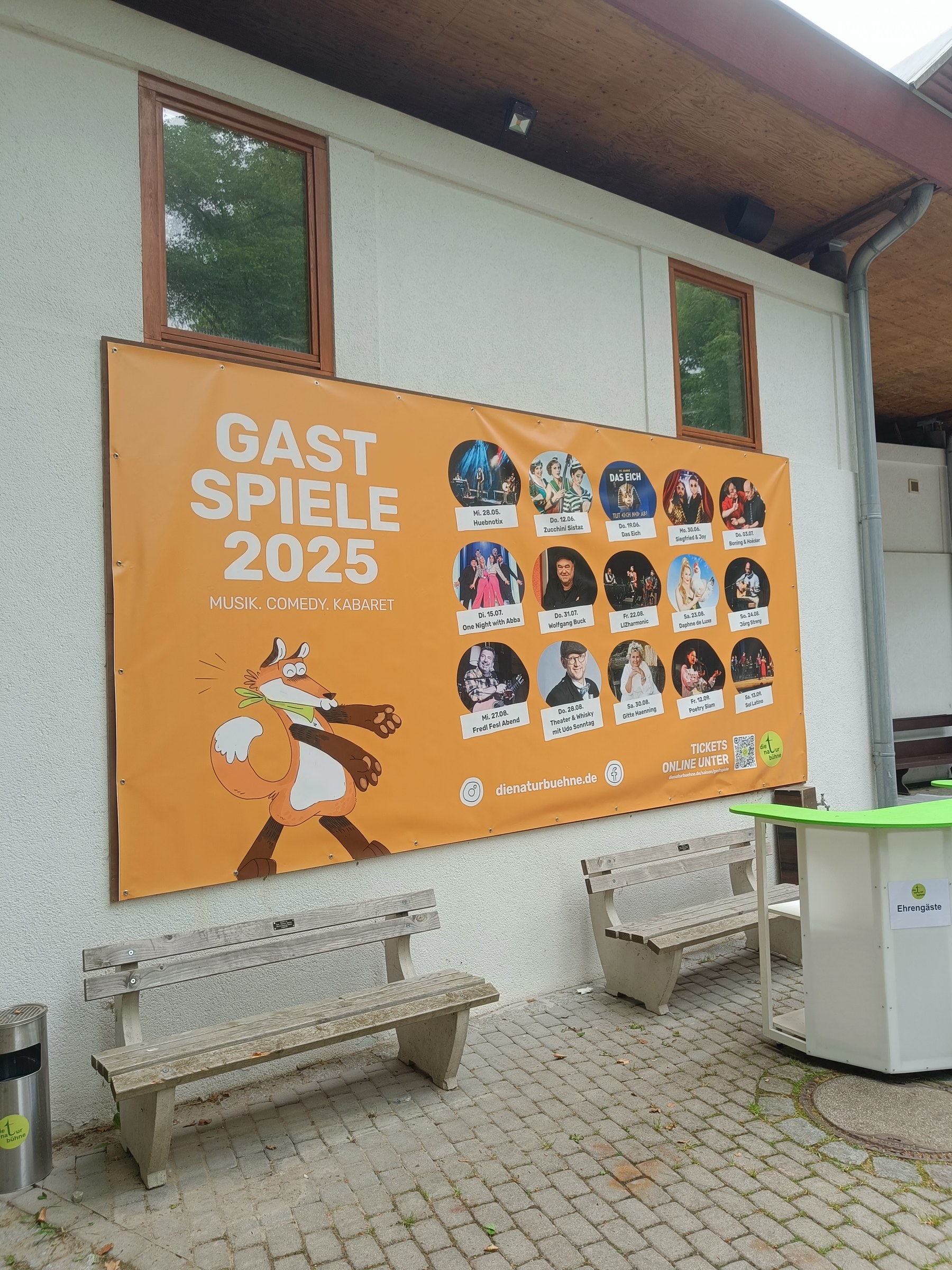 Oranges Banner mit Fuchs und Künstlerfotos an der Hauswand