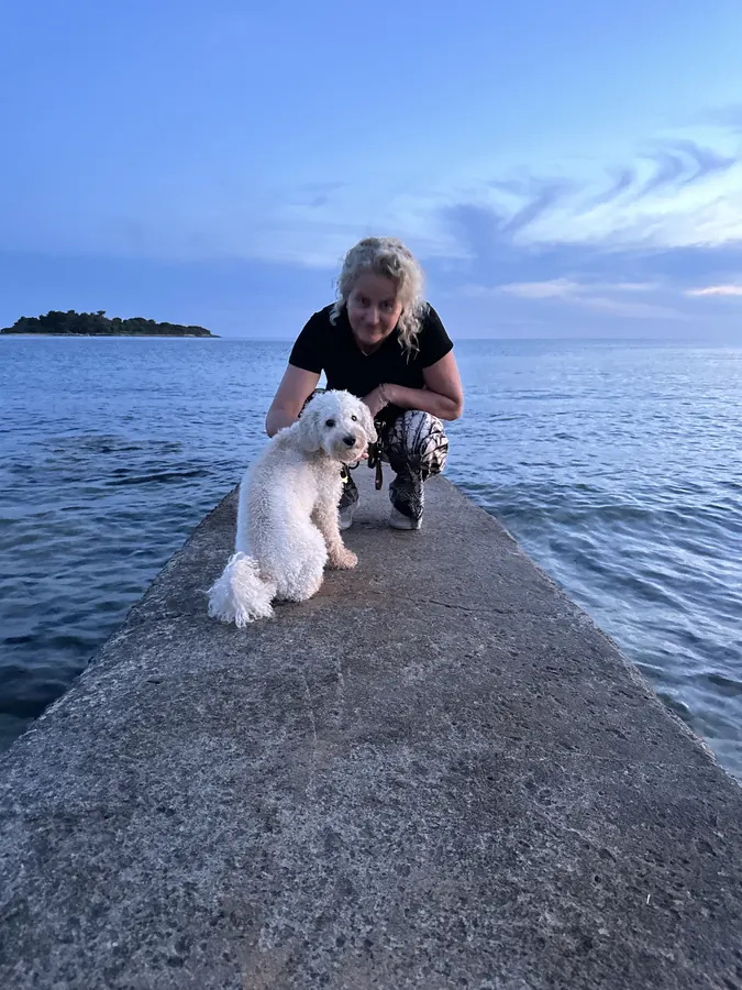 Ludwig sitzt auf einem Steg am Meer, daneben eine Frau