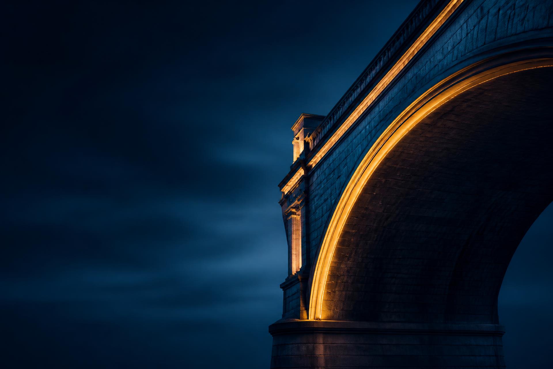 Illuminated stone bridge arch at dusk