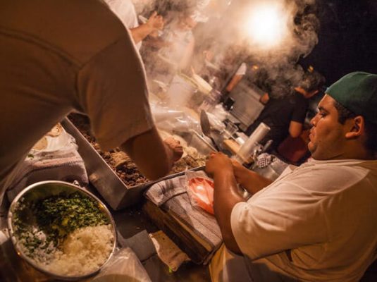 A cook prepares a taco, at a street stand, at night in Puerto Vallarta.