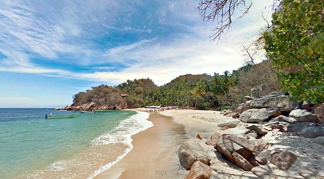 a bay and beach in Puerto Vallarta with a small boat anchored off shore.