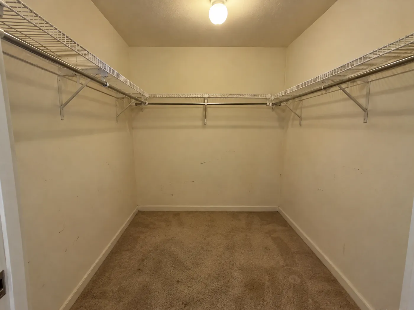 Before: empty walk-in closet with wire shelving and carpet