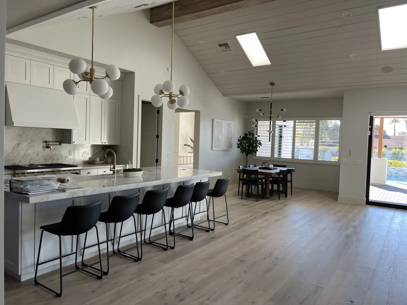 After: open kitchen, dining and living area with new wide-plank wood flooring