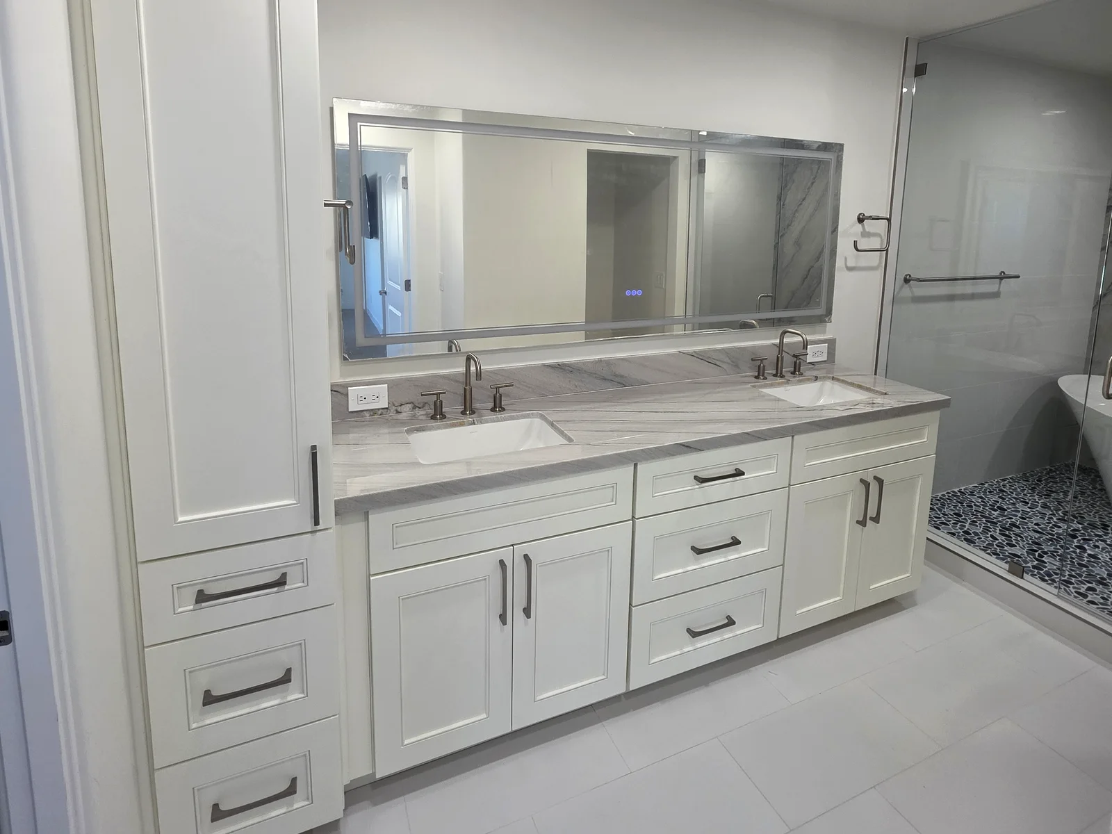 Double vanity with a veined stone top, undermount sinks and a linen tower