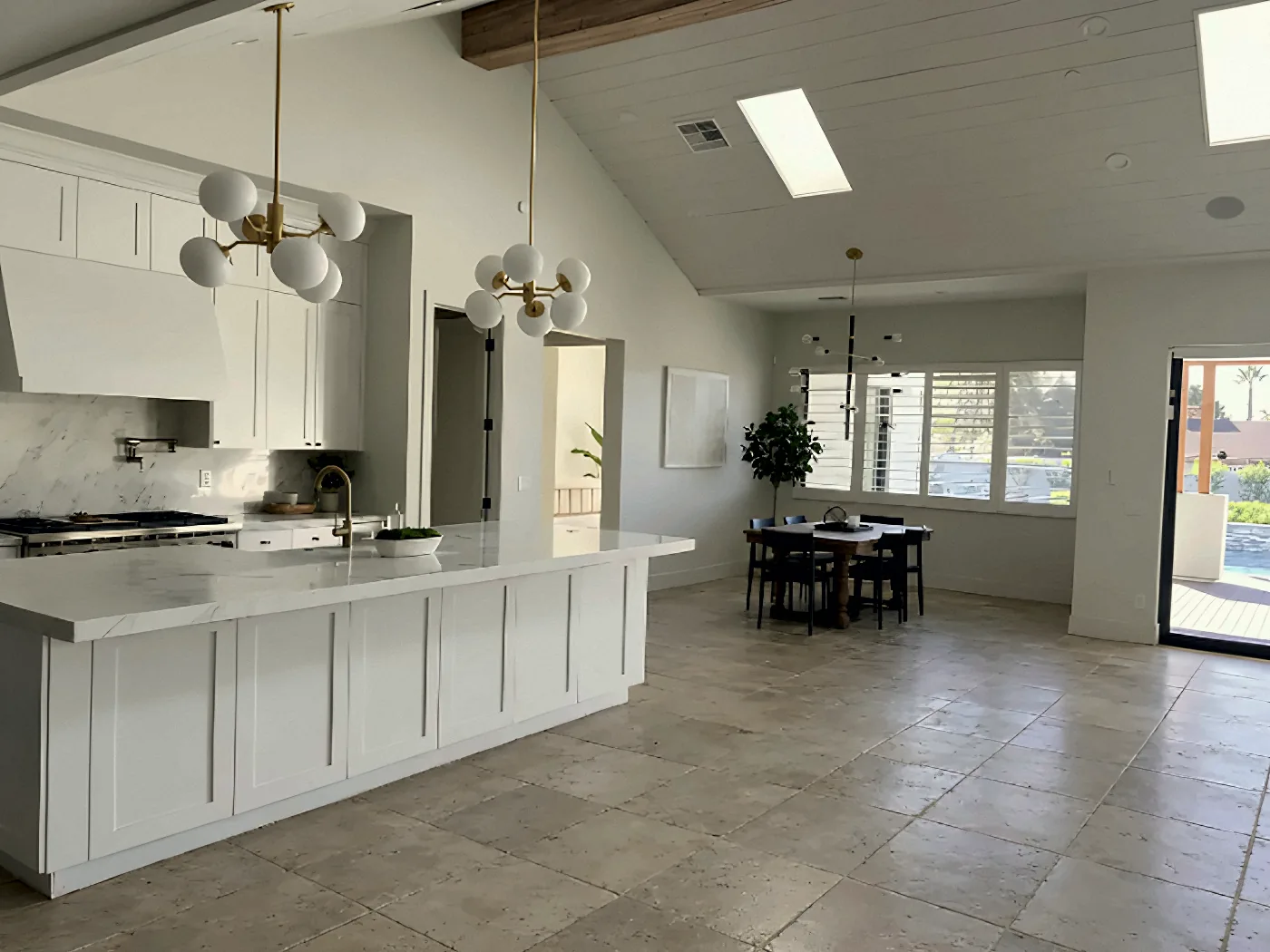 Before: open kitchen, dining and living area with worn stone tile floors