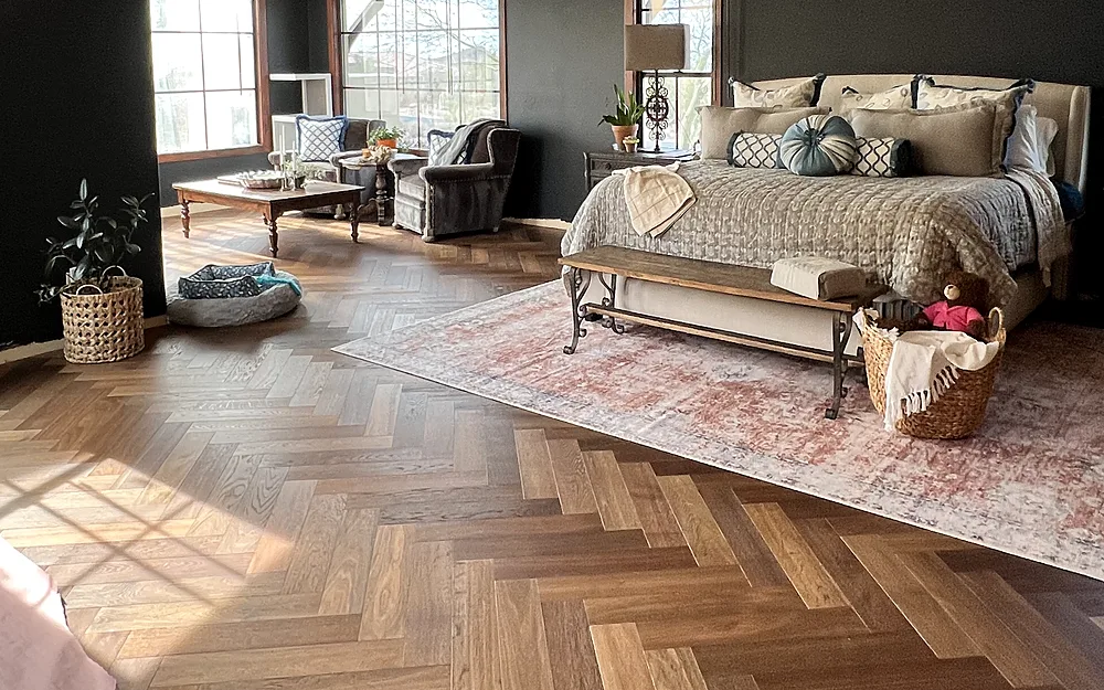 Warm herringbone wood flooring in a bright primary suite with a beamed ceiling