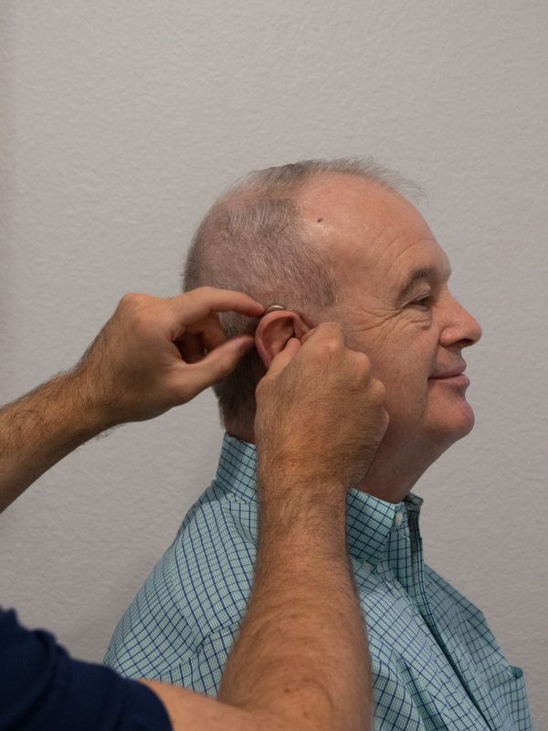 hearing aid being put on patient 