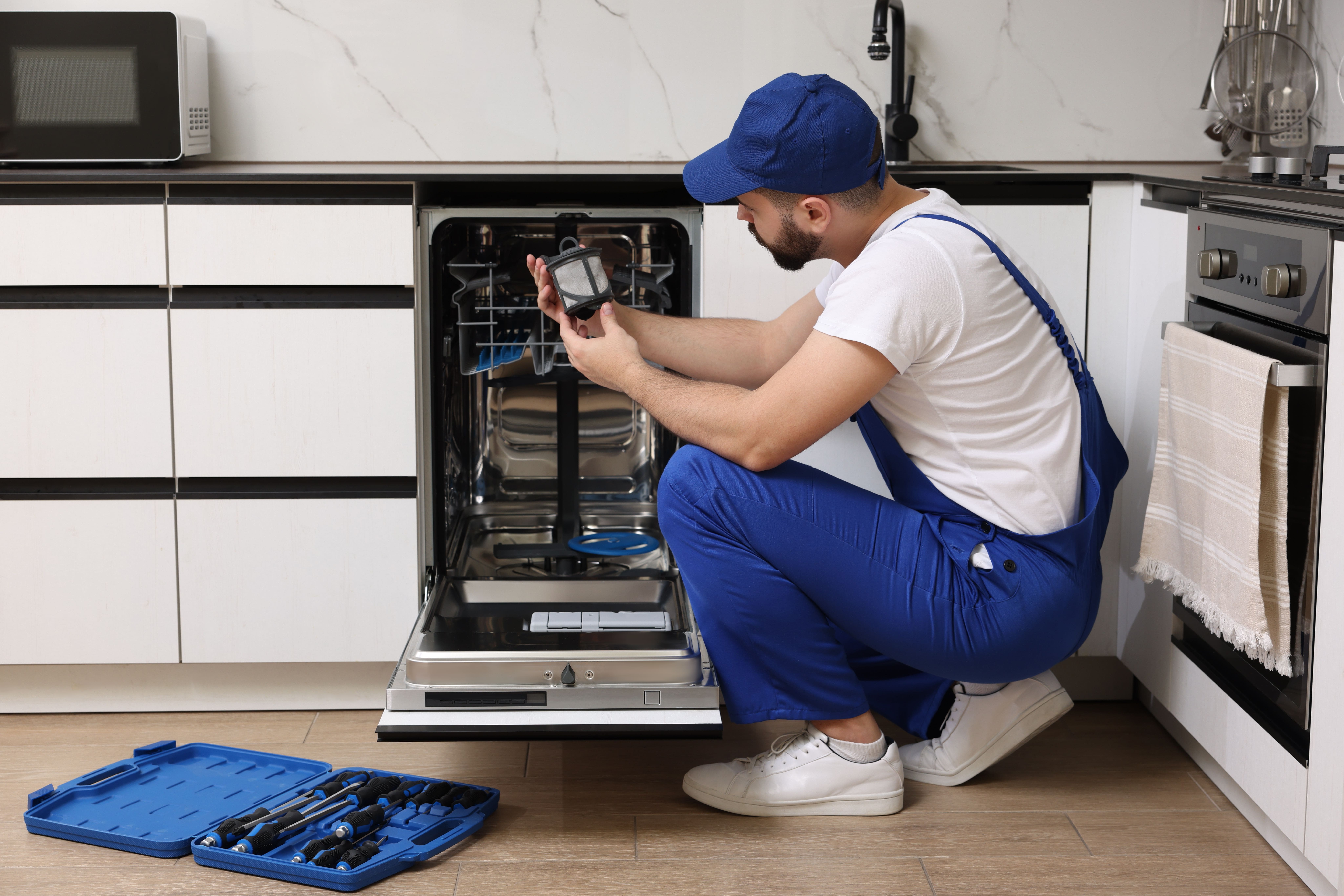 Technician performing dishwasher maintenance