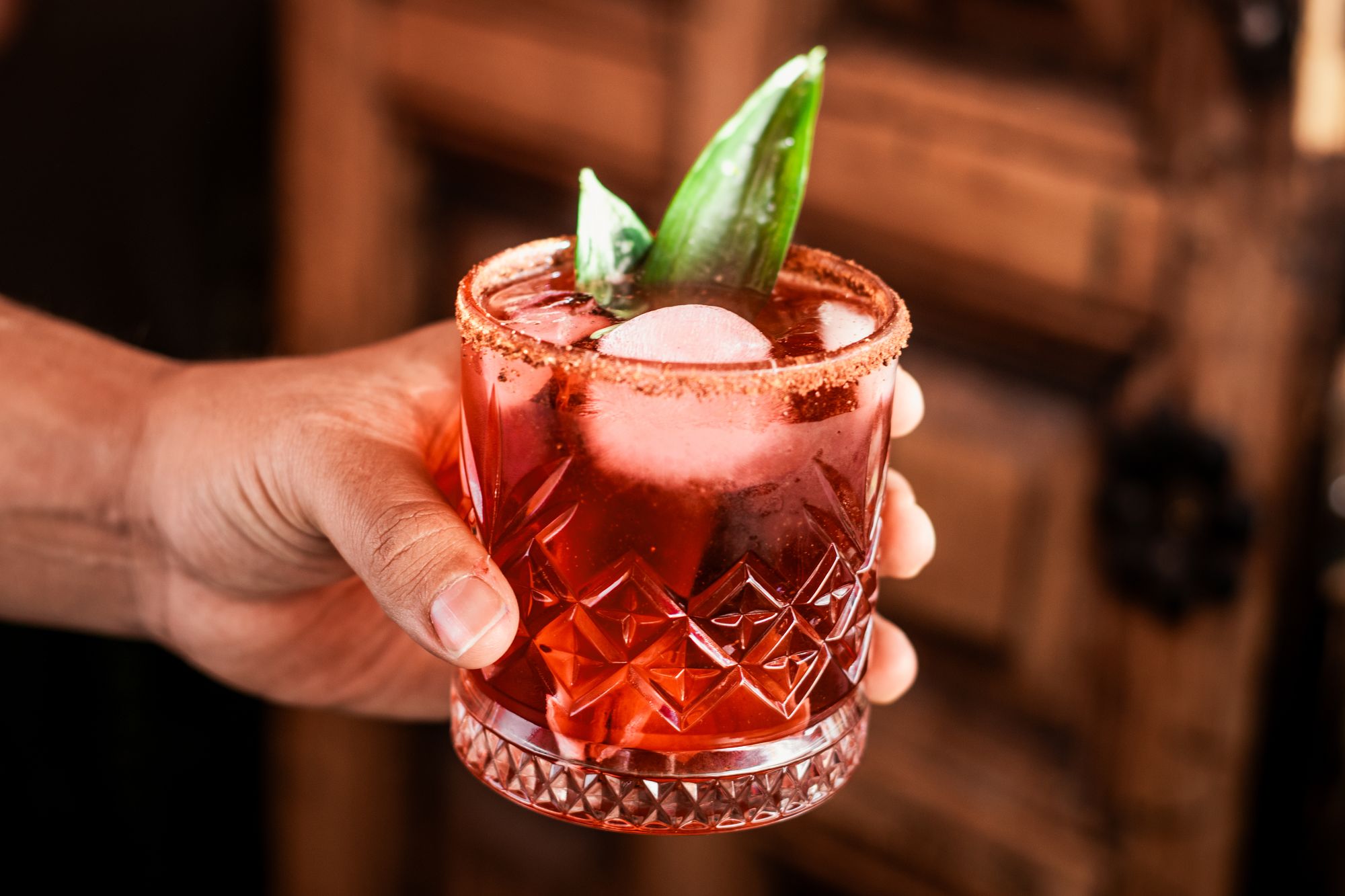 A red pox cocktail with a chile-salt rim and a pineapple-leaf garnish at La Independiente