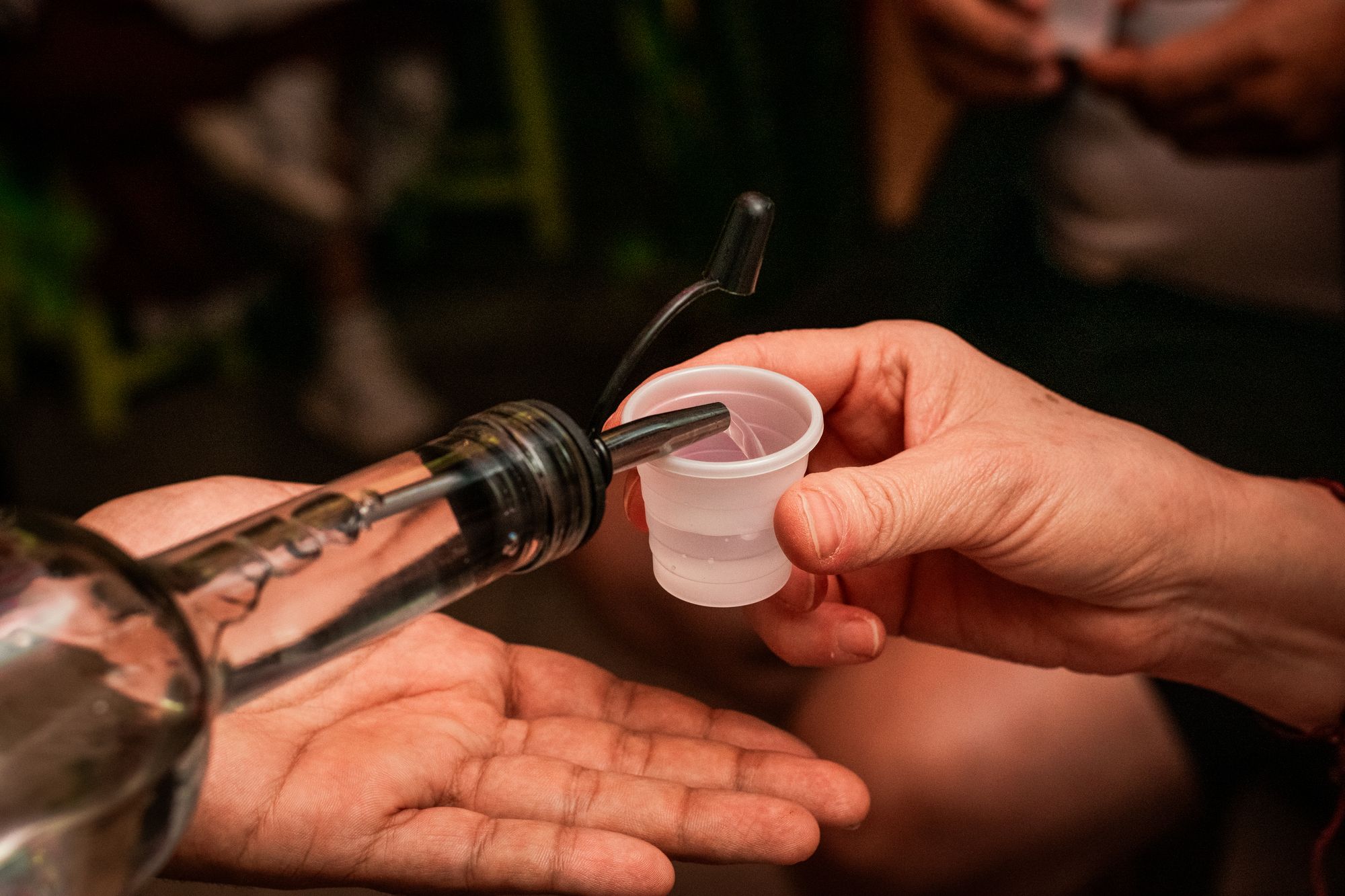 Pouring clear pox into a small tasting cup