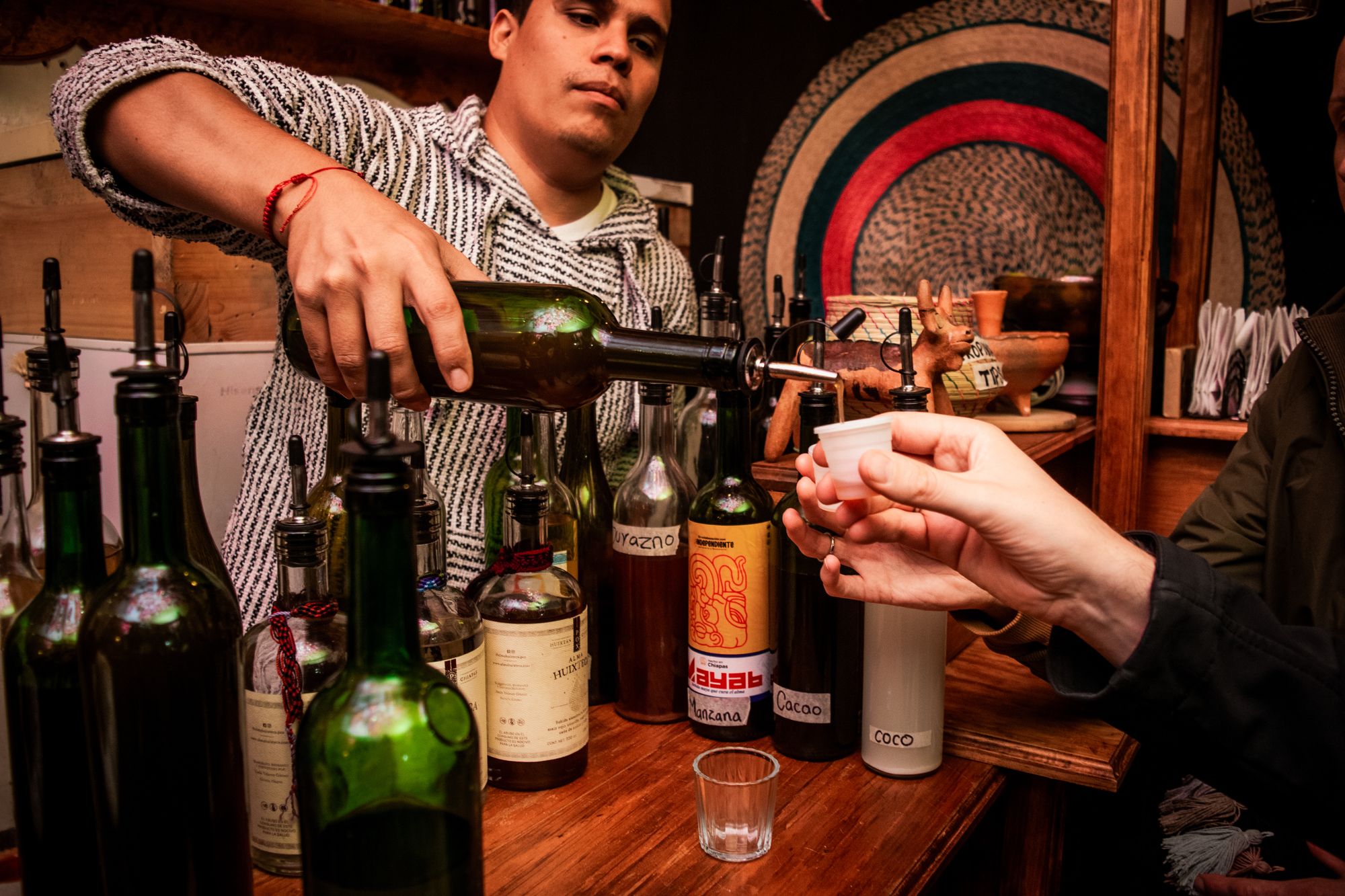 A La Independiente bartender pouring pox from a row of bottles on the bar