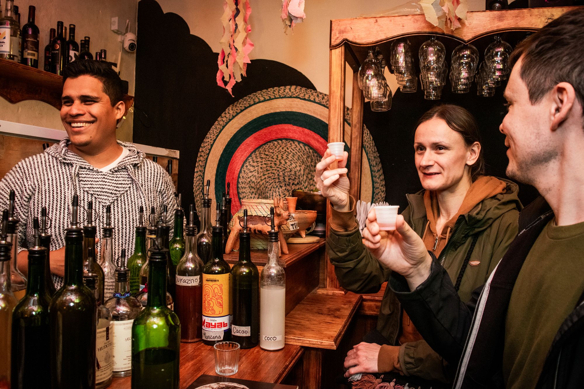 A La Independiente bartender pouring a free pox tasting for two guests in San Cristóbal