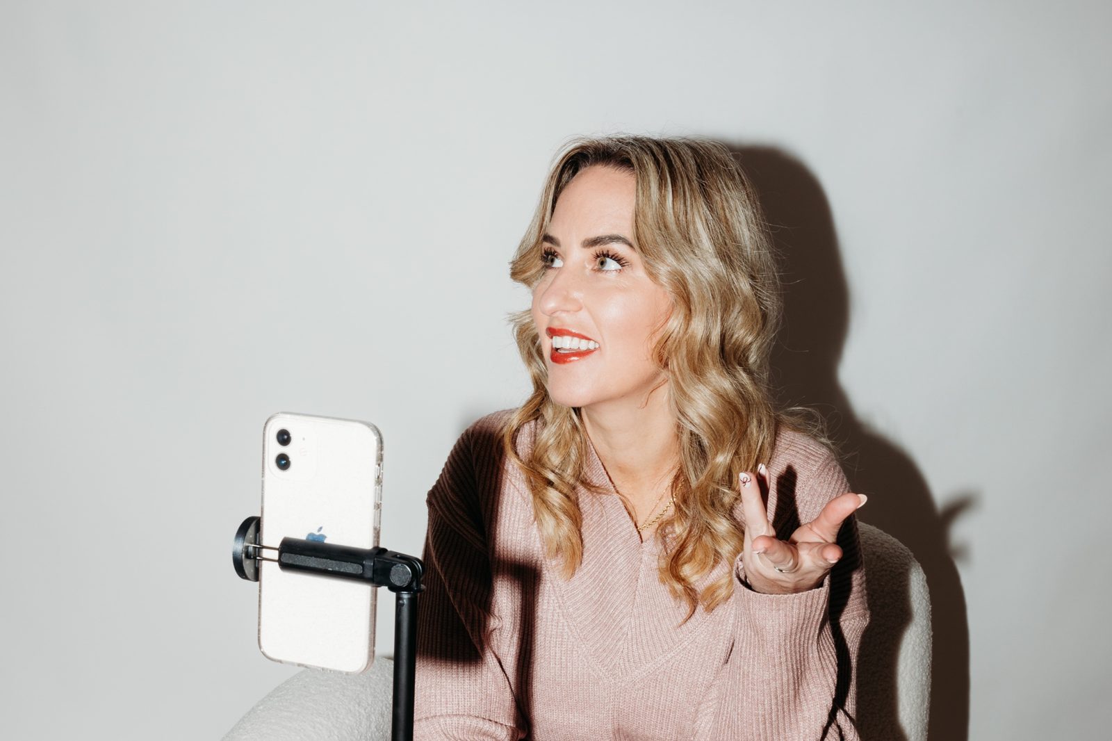 Gemma Heard in a pink jumper recording a voice note on her phone