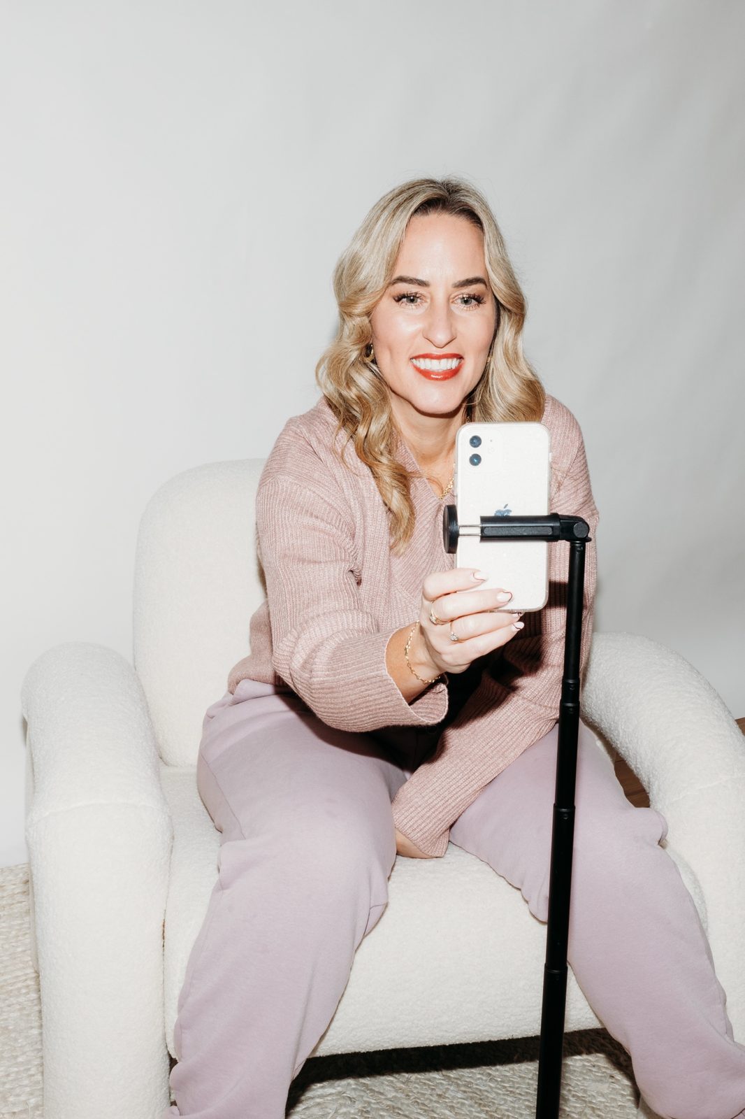 Gemma Heard sitting in a white chair, recording on her phone