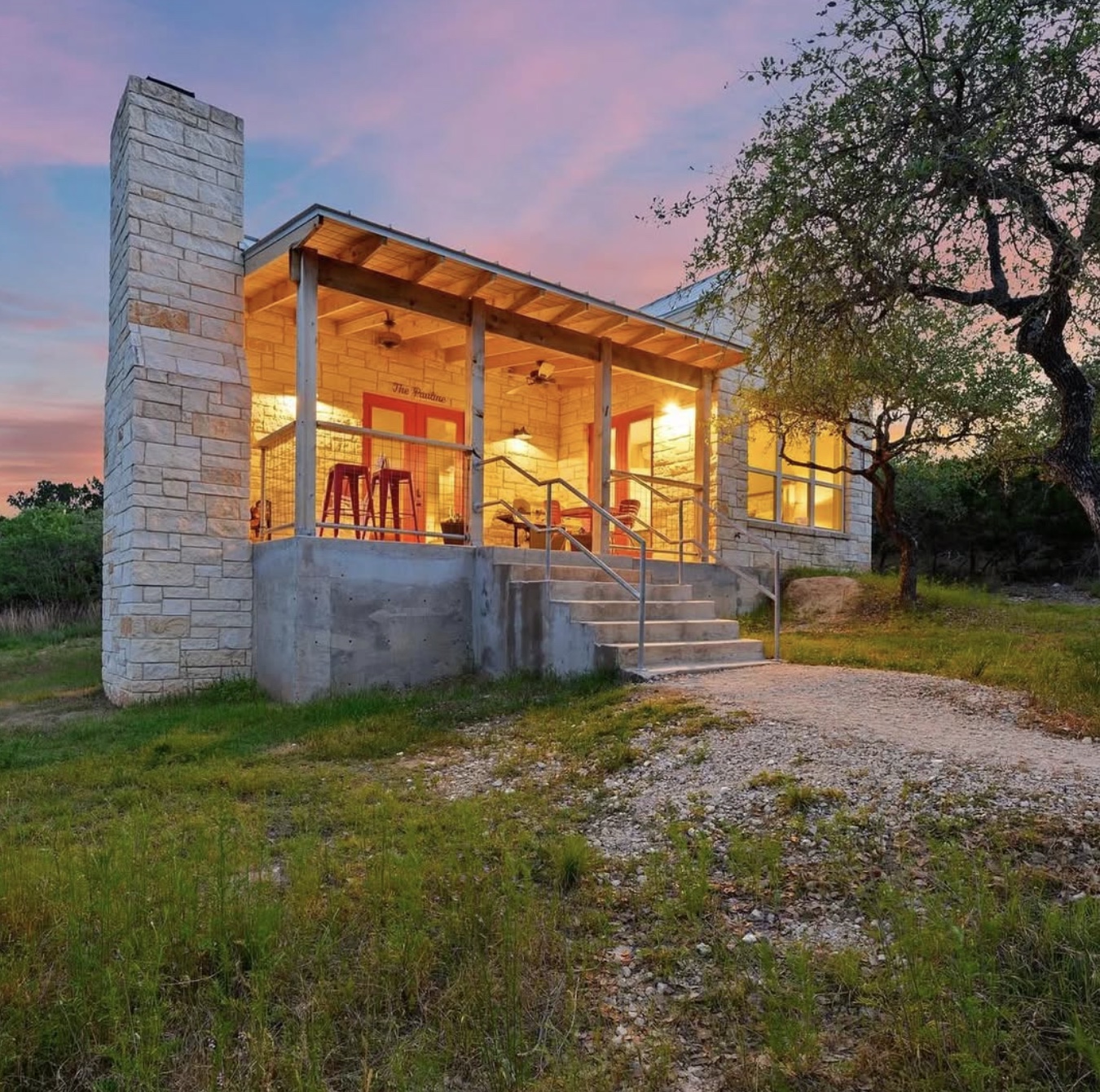 A limestone casita with a warmly lit porch beneath a pink evening sky at The UNRETREAT™.