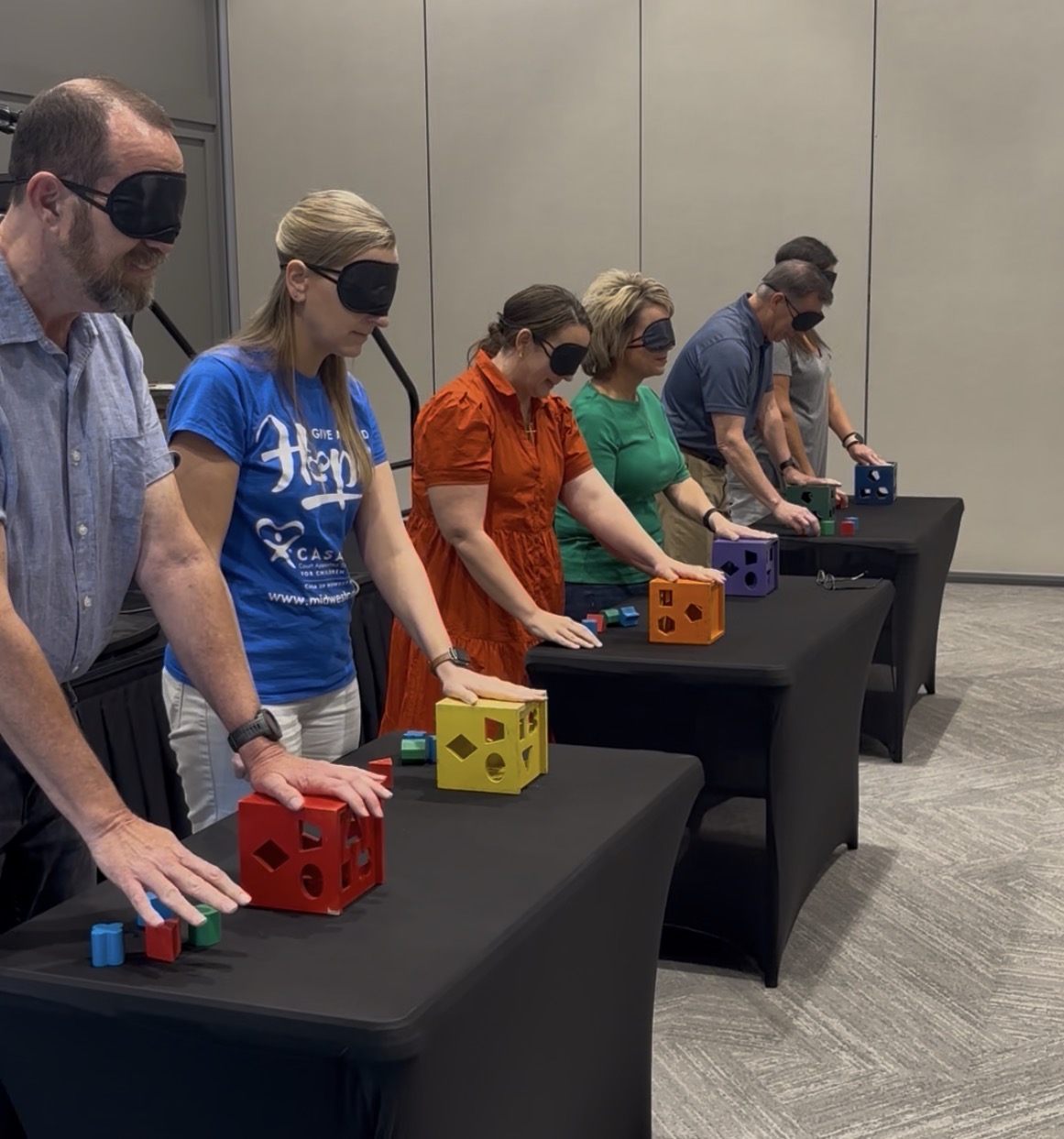 Blindfolded participants enjoy a colorful shape-sorting team challenge at a group event.