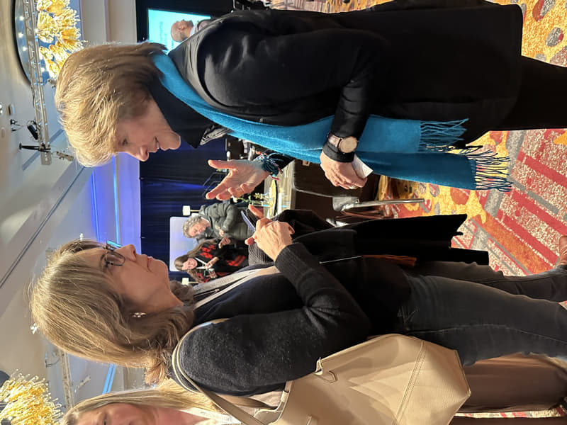 Melissa in conversation with Lynne Twist at a conference, discussing money, purpose, and sustainable financial perspectives.