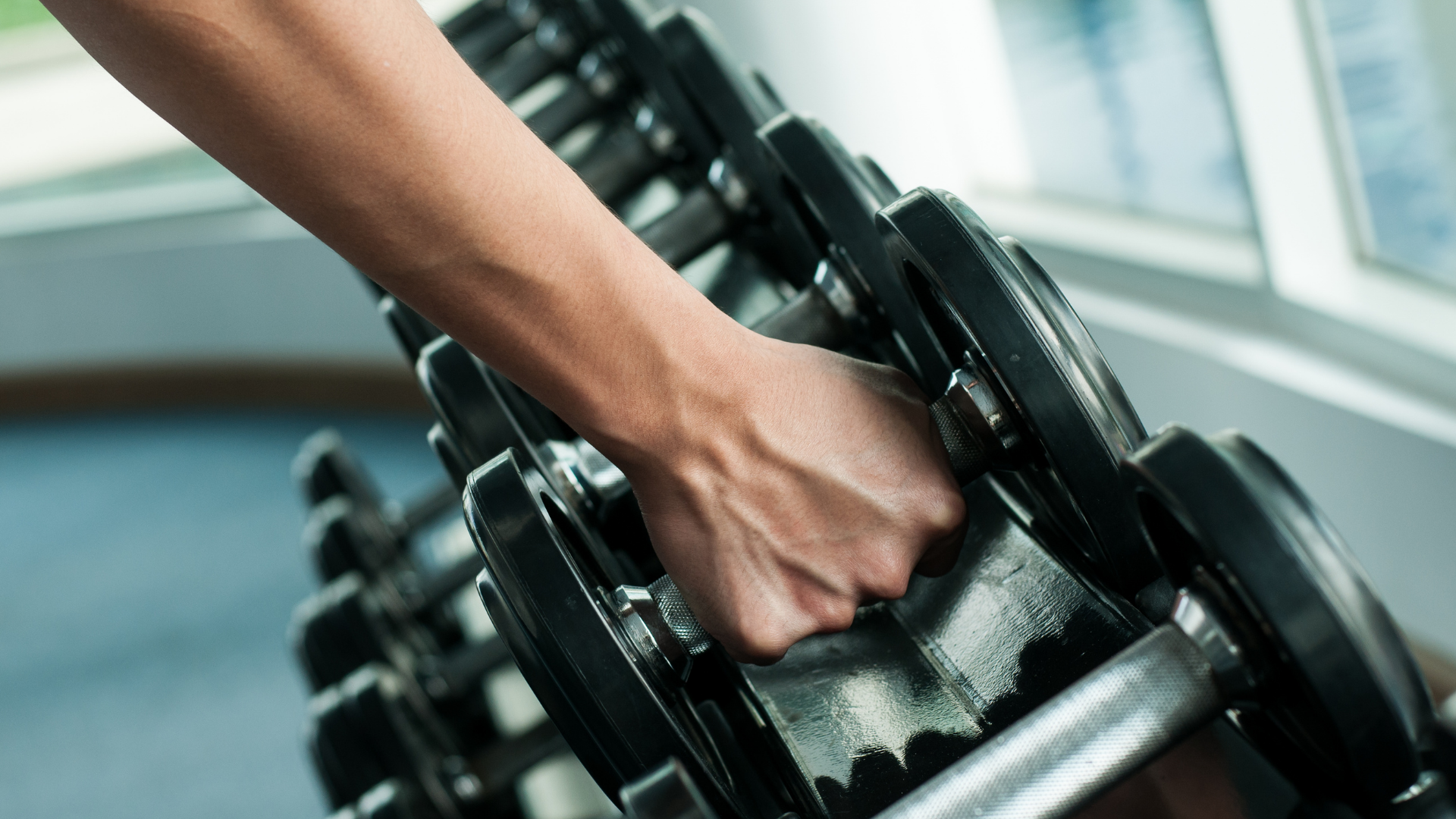Woman reaching for dumbbell in the gym
