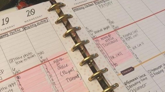 Woman's hands on a crowded planner next to a lit-up phone, a sign of burnout brain fog and mental overload Woman's hands on a crowded planner next to a lit-up phone, a sign of burnout brain fog and mental overload