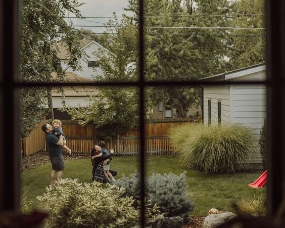Woman standing outside a doorway watching her family laugh, showing how high-achiever burnout pulls you away from the people you love Woman standing outside a doorway watching her family laugh, showing how high-achiever burnout pulls you away from the people you love
