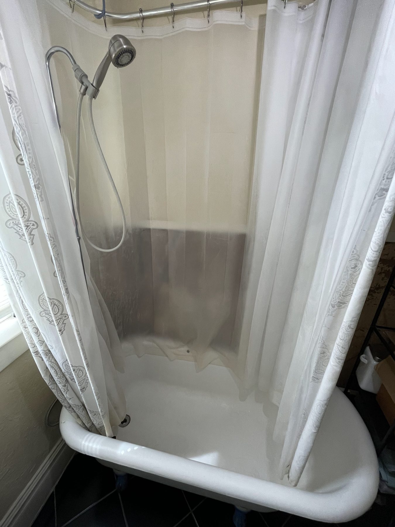 Unit 1 bathroom before, with a clawfoot tub and shower curtain