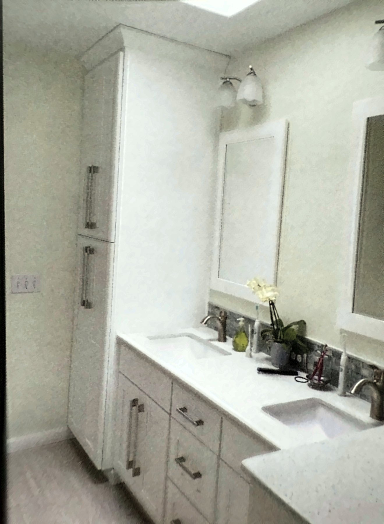 Master bathroom after the remodel, with a white double vanity and a tall linen cabinet