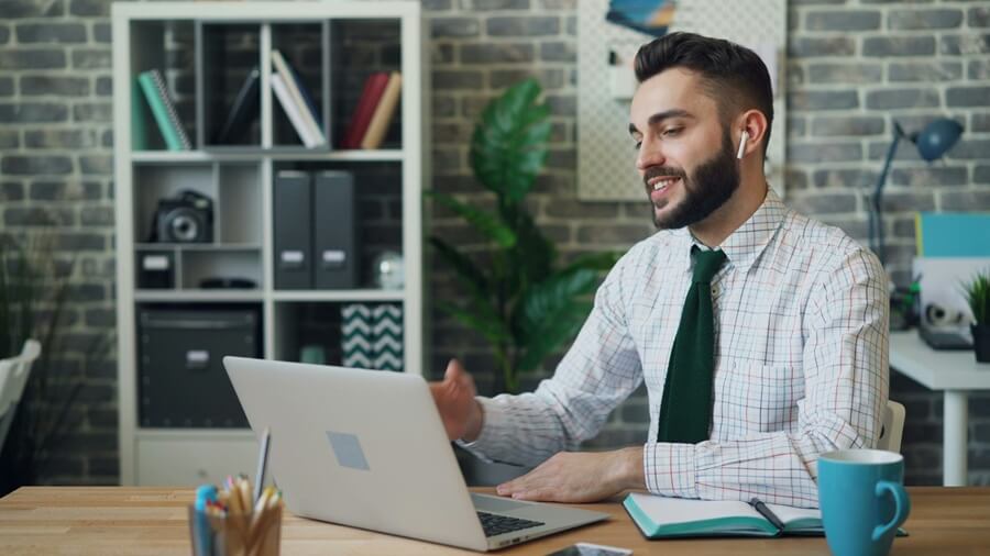 Un dirigeant souriant échange en visio depuis son bureau