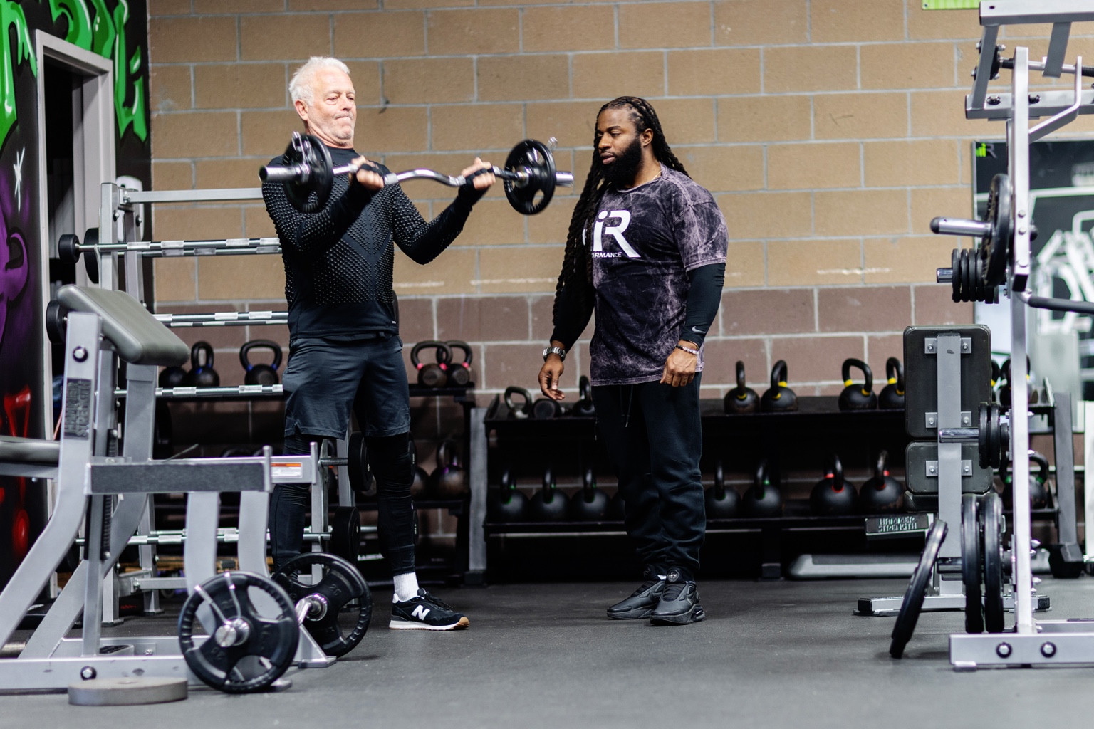 Coach Ejay guiding a client through strength training at iRISE