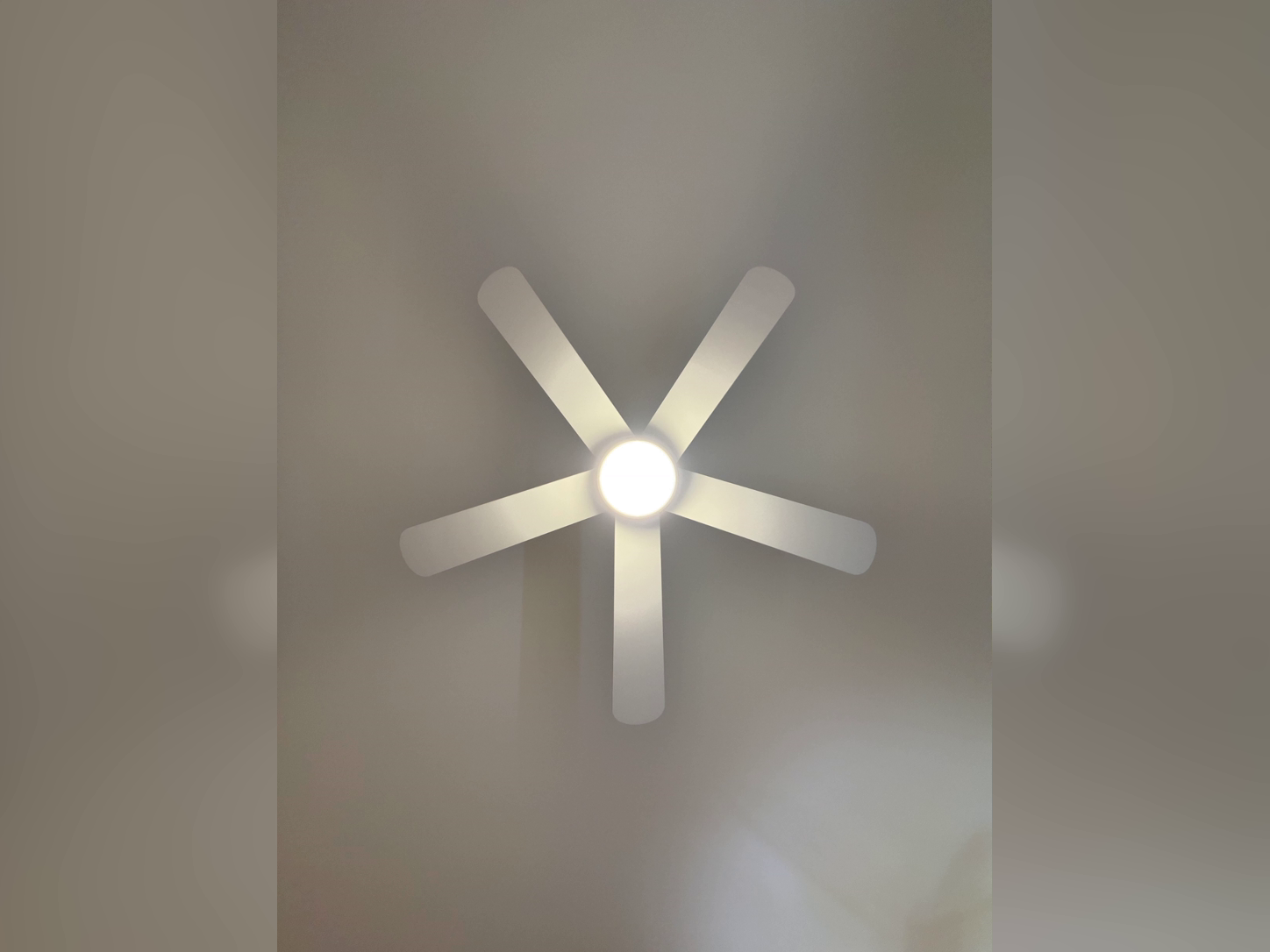 Five-blade ceiling fan with a lit centre light, installed on a ceiling