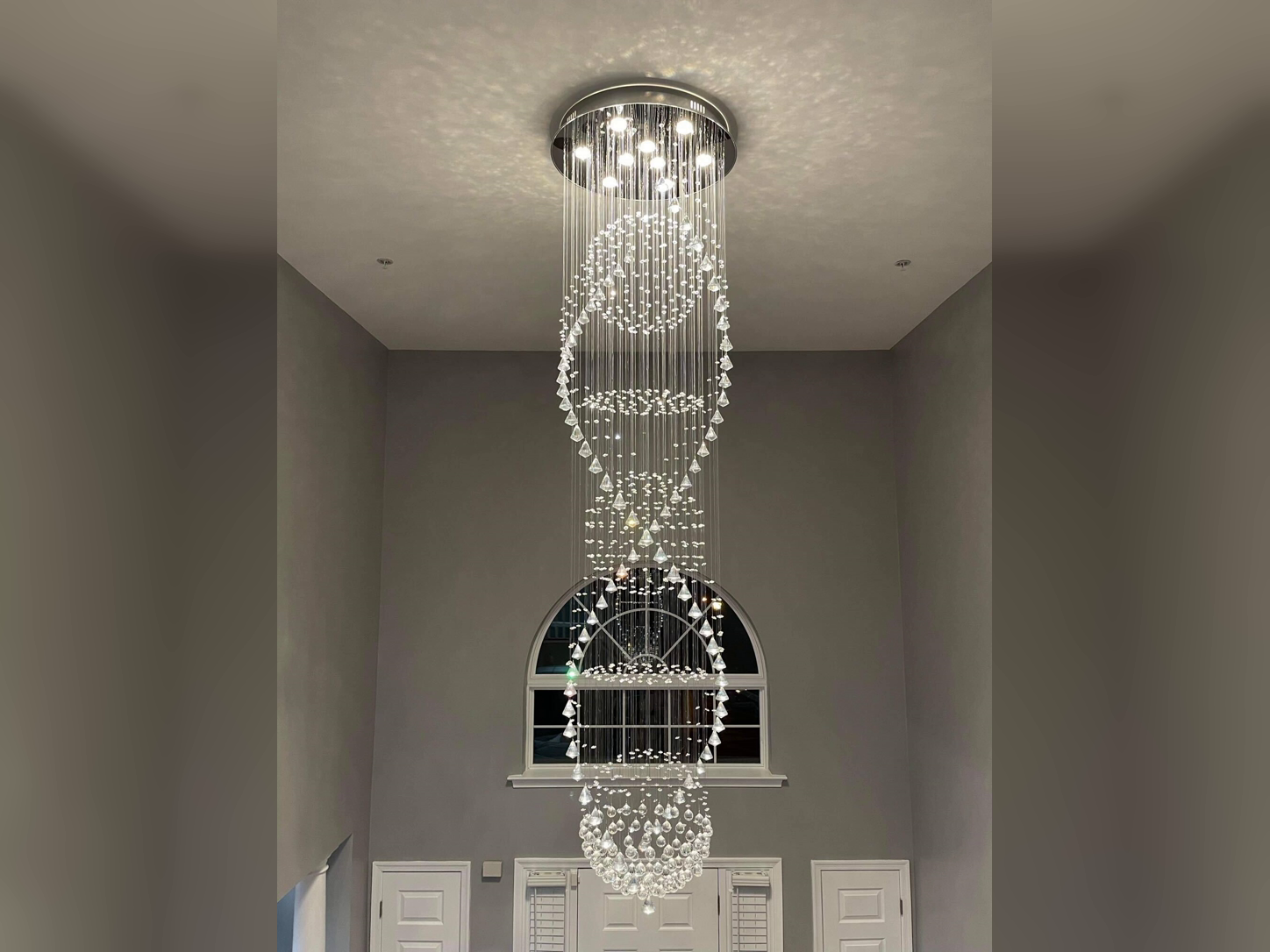 Crystal chandelier installed in a high-ceilinged entryway