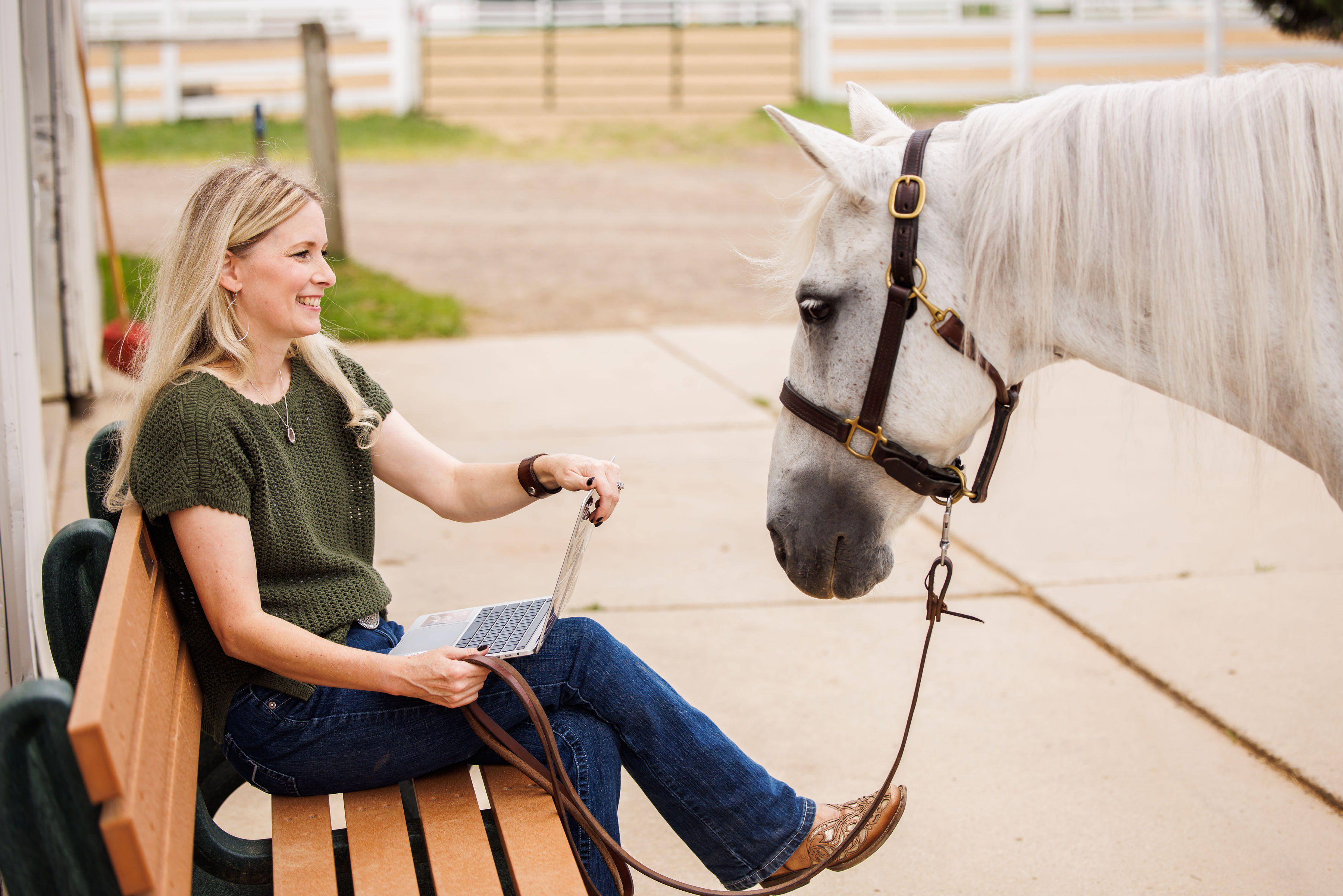 Jamie working on a laptop beside a horse