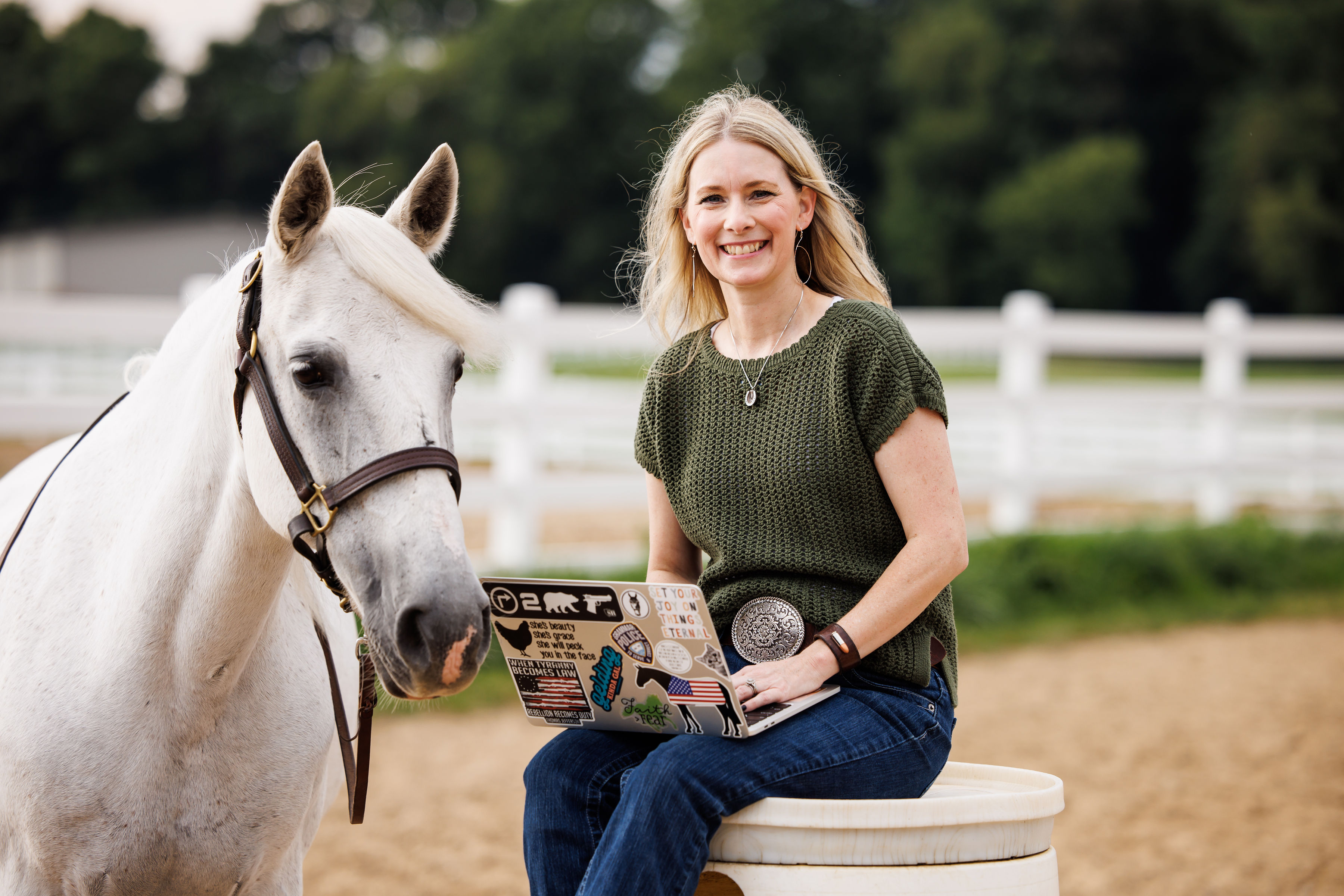 Jamie working on a laptop beside her horse