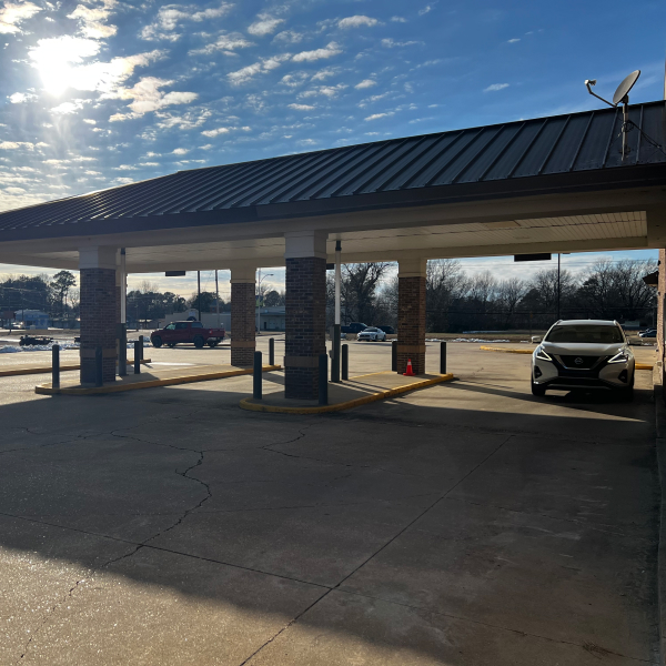 Pharmacy drive-thru area with covered service lanes and vehicles outside the building.