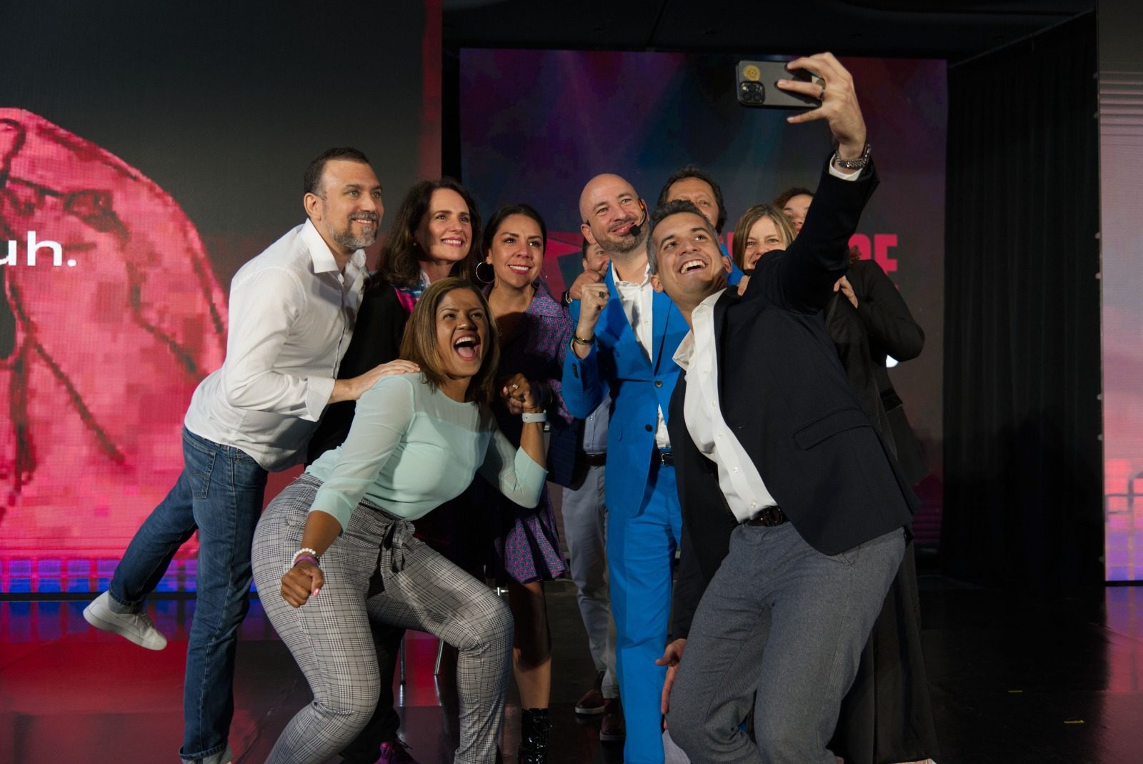 Selfie de grupo en el escenario, con ponentes y asistentes.