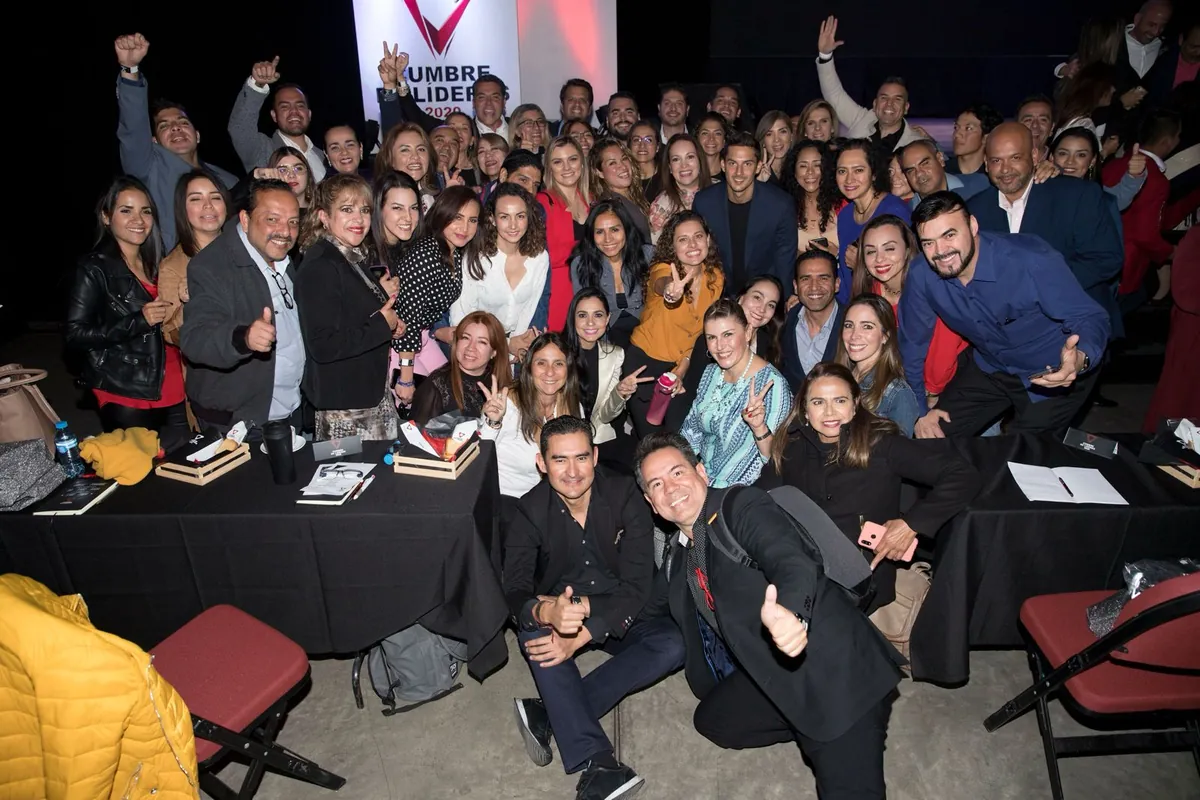 Foto grupal de asistentes de la Cumbre con Jaime Lokier al centro, frente al escenario.
