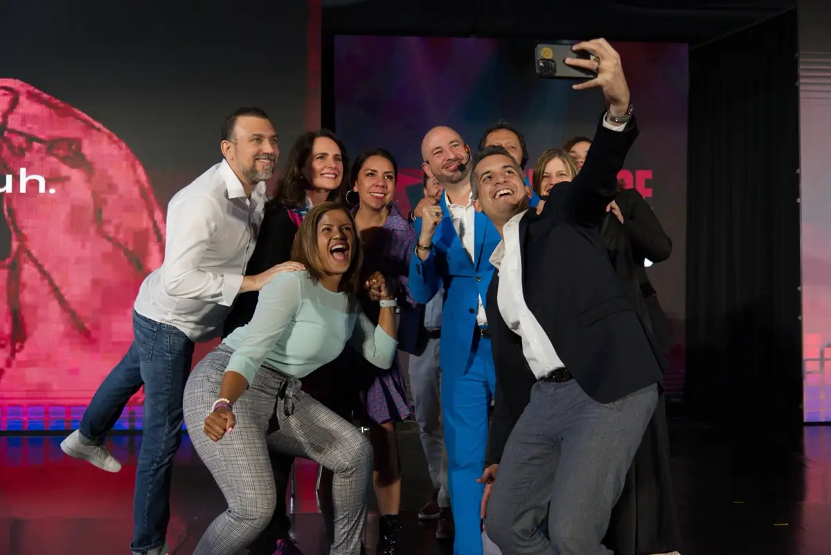 Selfie de grupo en el escenario, con ponentes y asistentes.