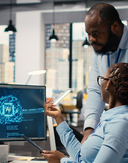 Two colleagues reviewing AI dashboards on a monitor