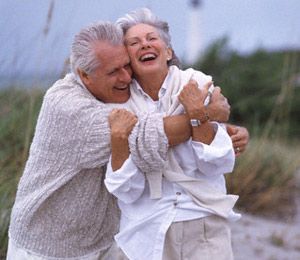 A couple embracing and laughing together outdoors by the dunes.