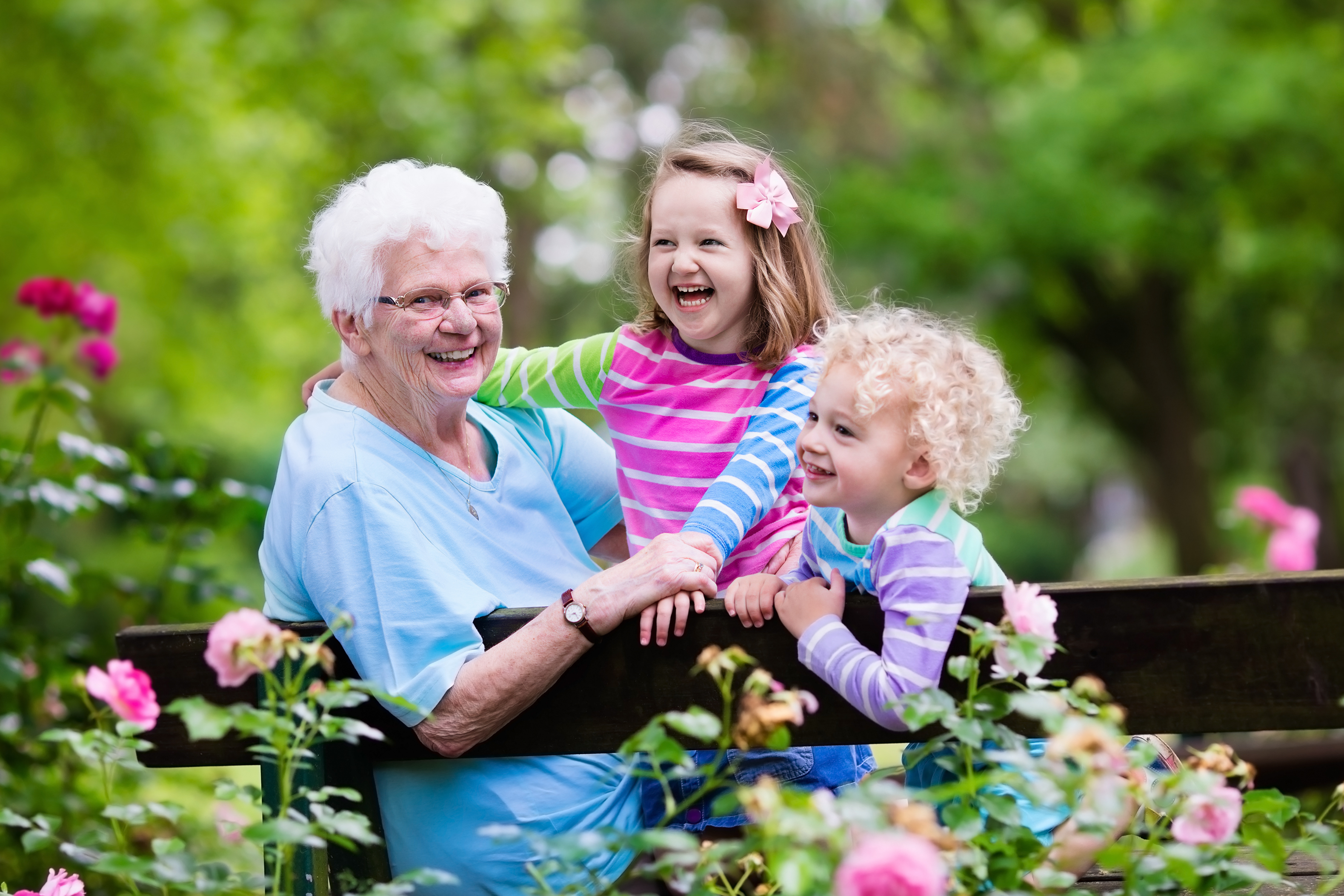 Grandparents on a garden bench with their two young grandchildren.