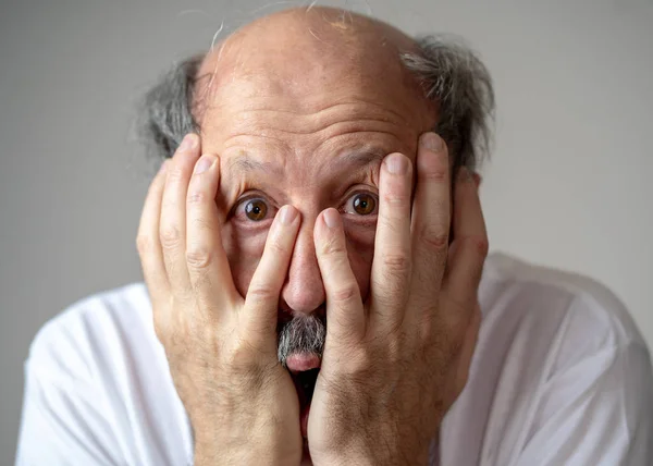A man with his hands to his face, looking overwhelmed.
