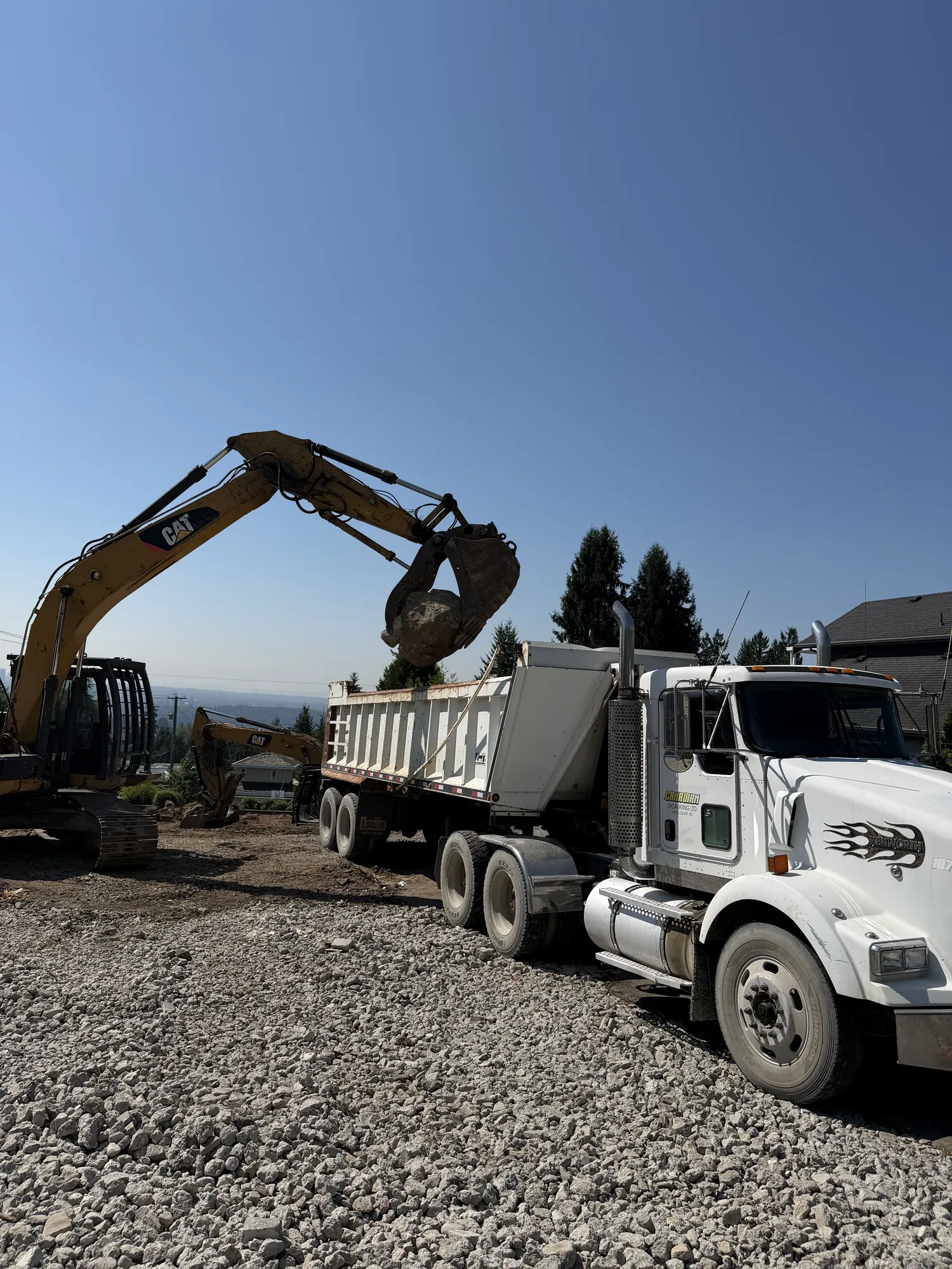 Slinger truck spreading gravel fill on a construction site in Delta BC