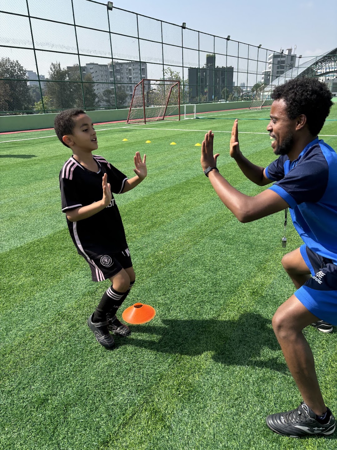 A PYA coach and young footballer sharing a high-five during practice