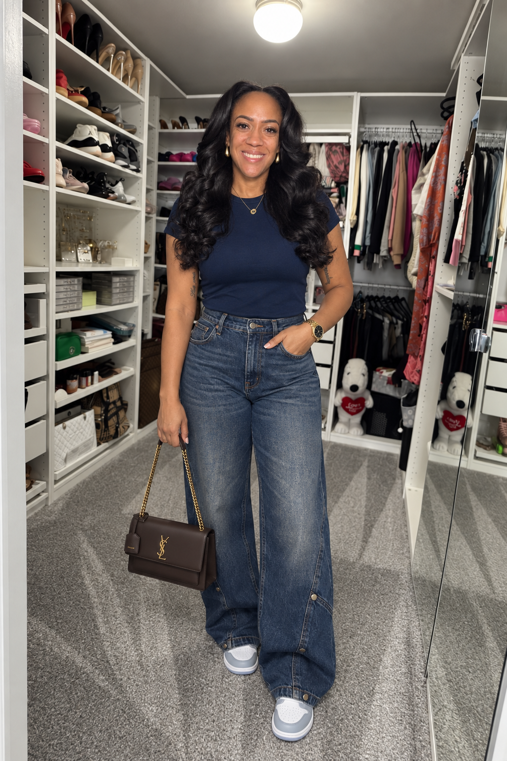 AI-created image of TT in her original closet, wearing Know The Vibes High Rise Hem Adjuster Jeans in Dark Wash, Alyssa Crew Neck Top in Navy, styled with Jordan Air Jordan 1 Mid in White/Wolf Grey/Aluminum, Saint Laurent Sunset Medium in smooth leather in Dark Chocolate, Anne Klein Bracelet Watch AK/2158BKGB in Gold/Black, PAVOI 22 mm teardrop earrings in Yellow Gold.