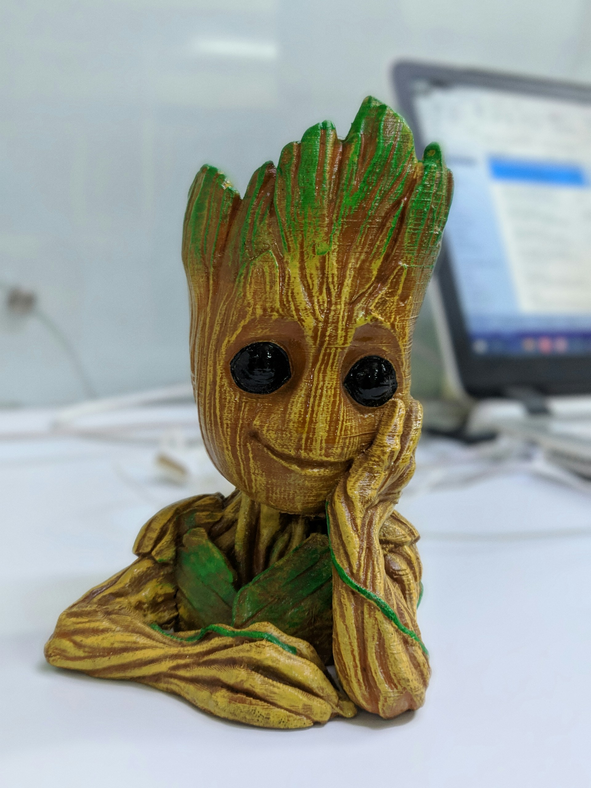 Groot action figure with a happy face on a work desk