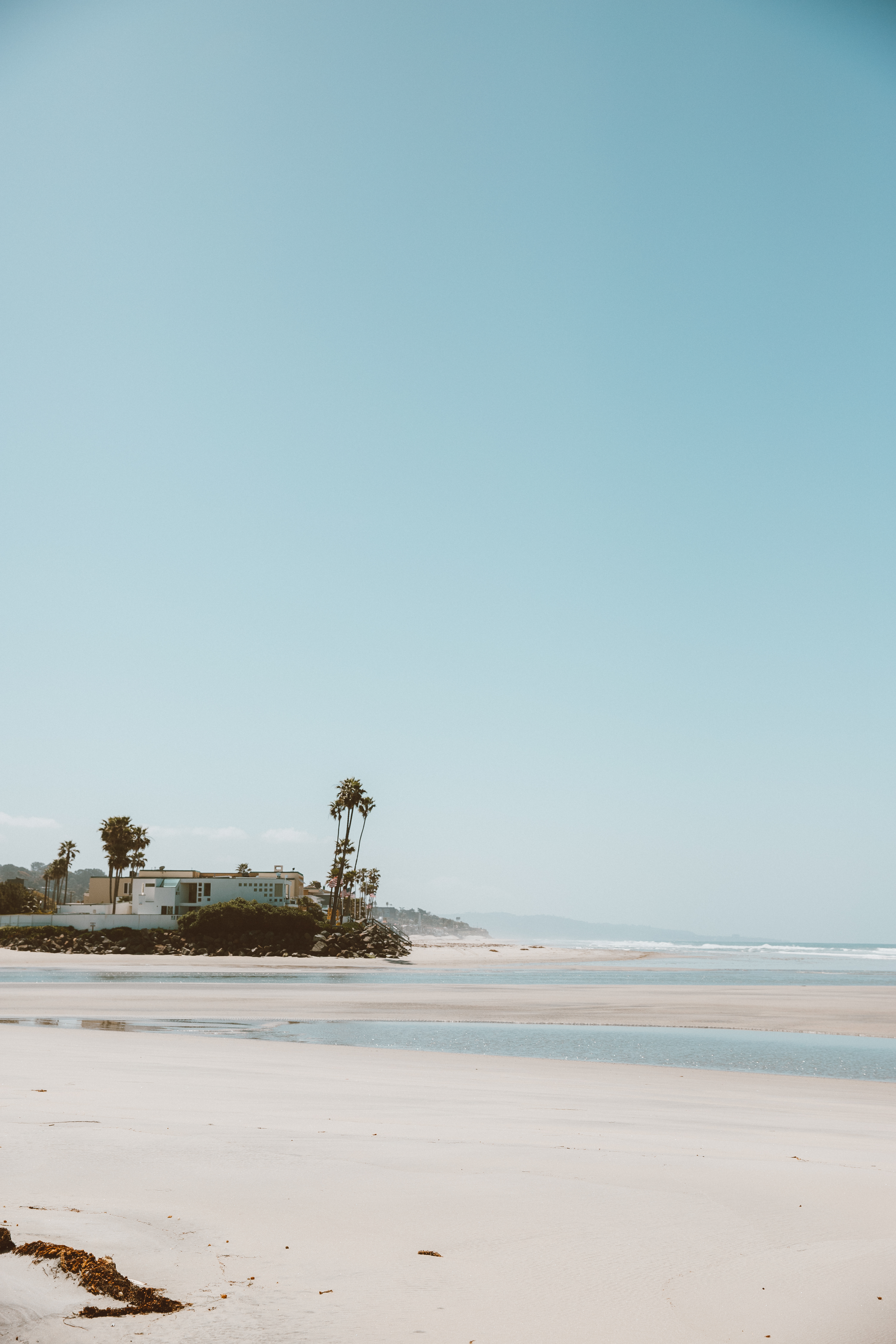 A quiet San Diego beach at low tide under a clear blue sky