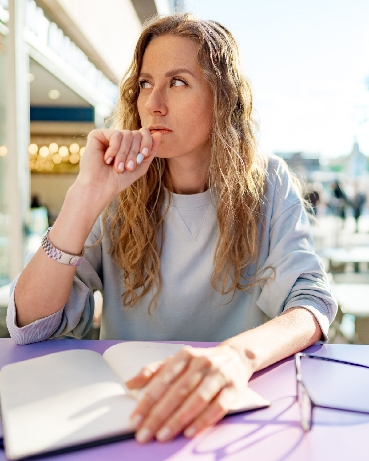 Thoughtful woman journaling at a cafe